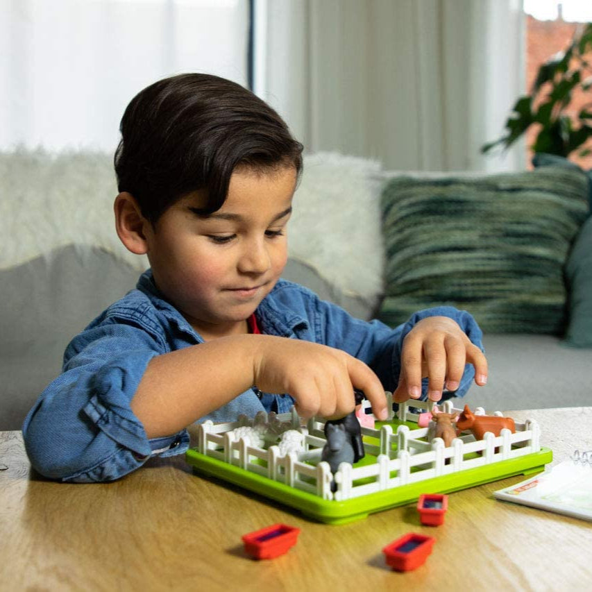Smart Games Smart Farmer educational toy; child arranges plastic farm animals on a green board