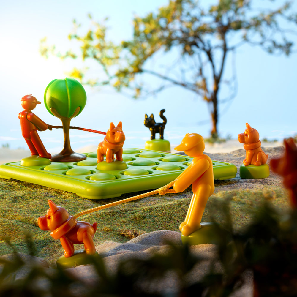 Smart Games Walk the Dog educational toy set with orange figures guiding dogs on a green grid mat