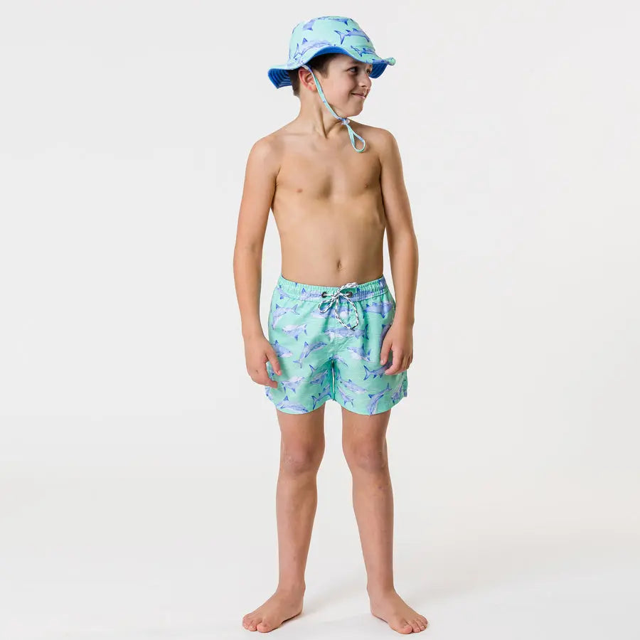 Snapper Rock Minty Shark Volley Board Short on a boy standing in mint-green swim shorts with blue shark print.