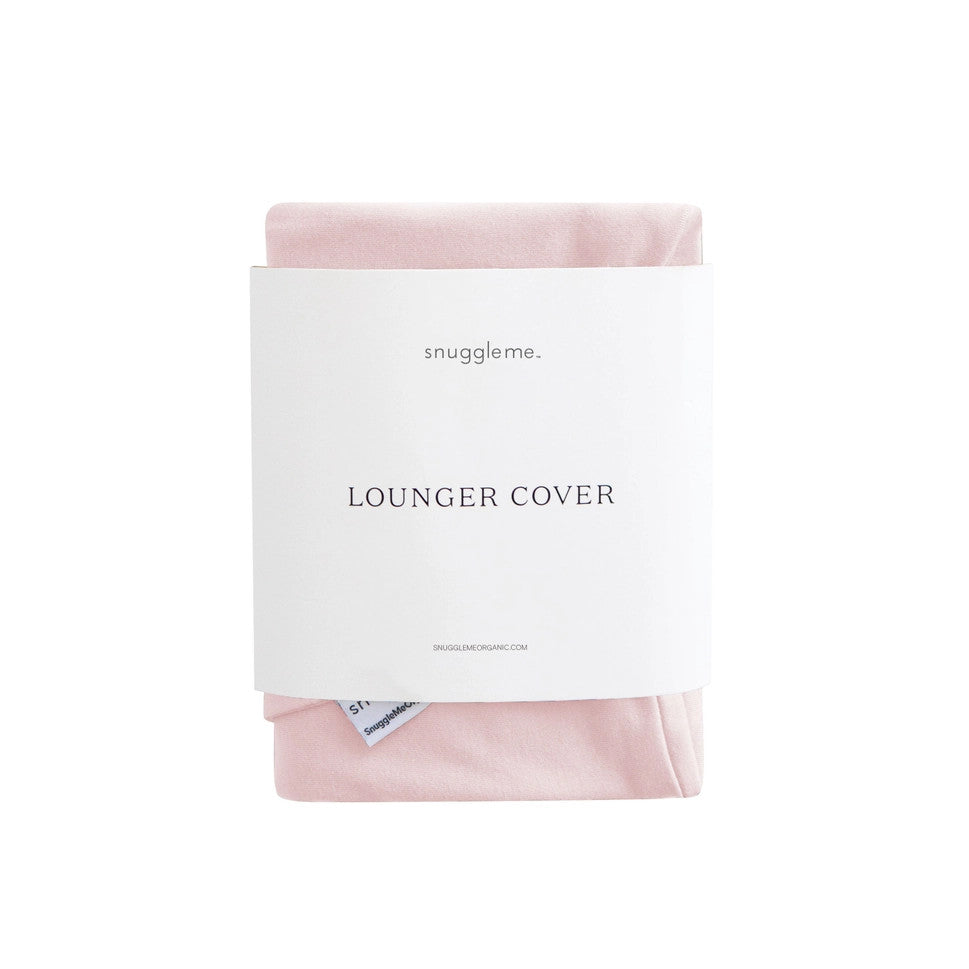 Snuggle Me Organic Infant Lounger Cover in soft pink, shown folded and tucked in its white packaging.