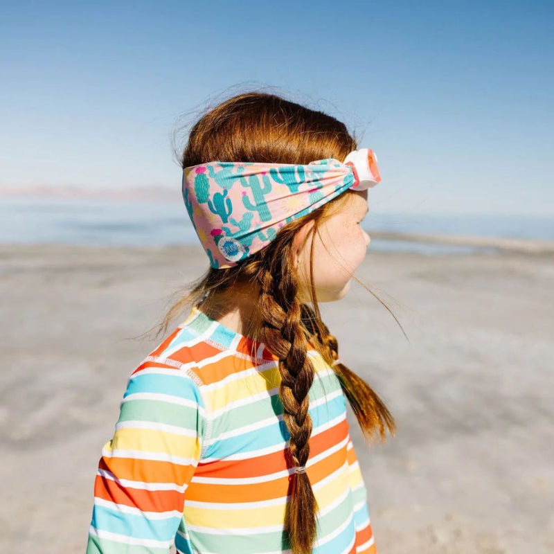 Splash Swim Goggles Desert headband with pastel cactus print worn by a girl at the beach