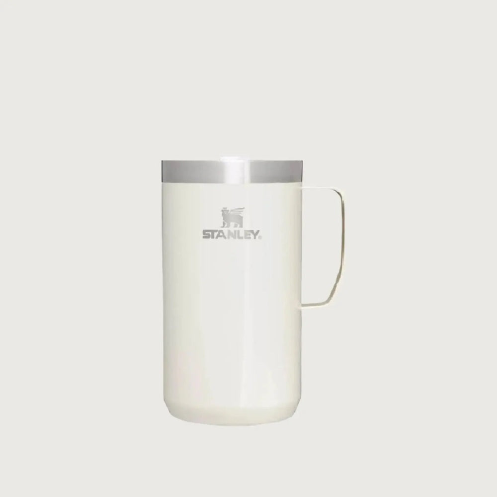 Stanley Classic Stay-Hot Camp Mug 24 oz, white with stainless lid, being held by its metal handle.