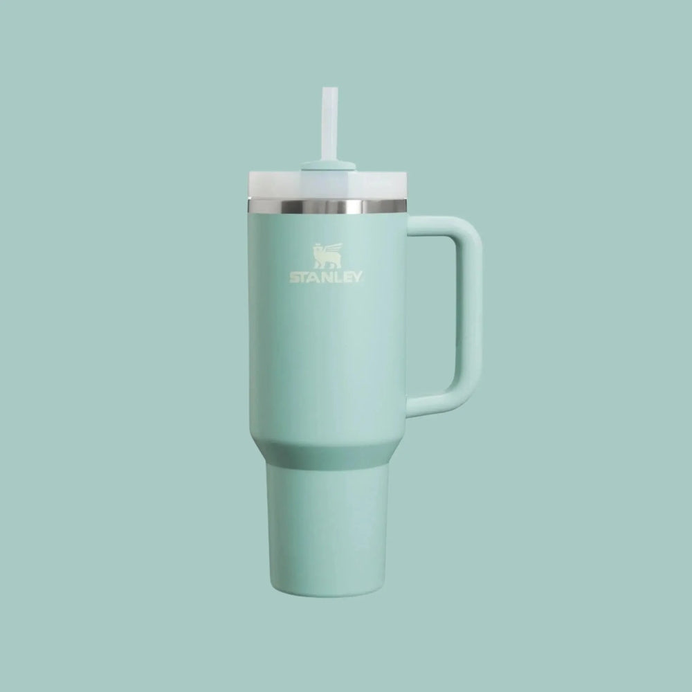 Stanley The Quencher H2.0 Flowstate 40 oz tumbler in mint green with straw lid and built-in handle, straw inserted through lid showing use
