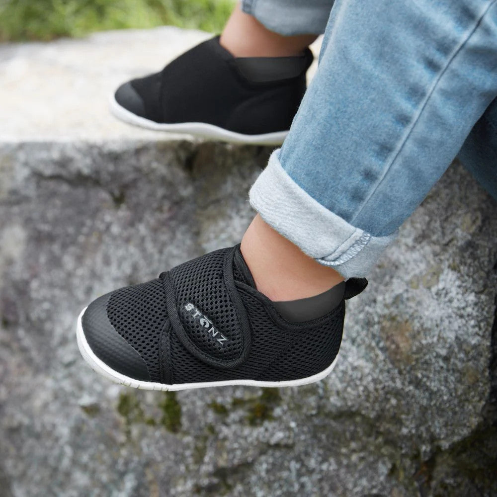 Stonz Cruiser Original Baby Shoes Black on a toddler's feet; breathable mesh, Velcro strap, white sole.