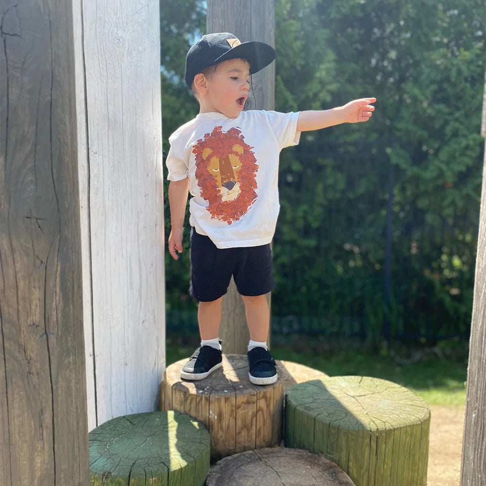 Stonz Cruiser Original Toddler Shoes Haze Navy Tonal; toddler on a wood stump wearing black sneakers with white soles outdoors.