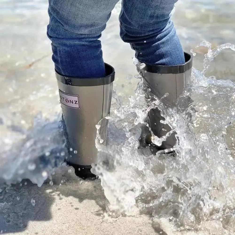 Stonz Rain Boots Metallic Grey; child in jeans splashes through shallow surf wearing waterproof rubber boots.
