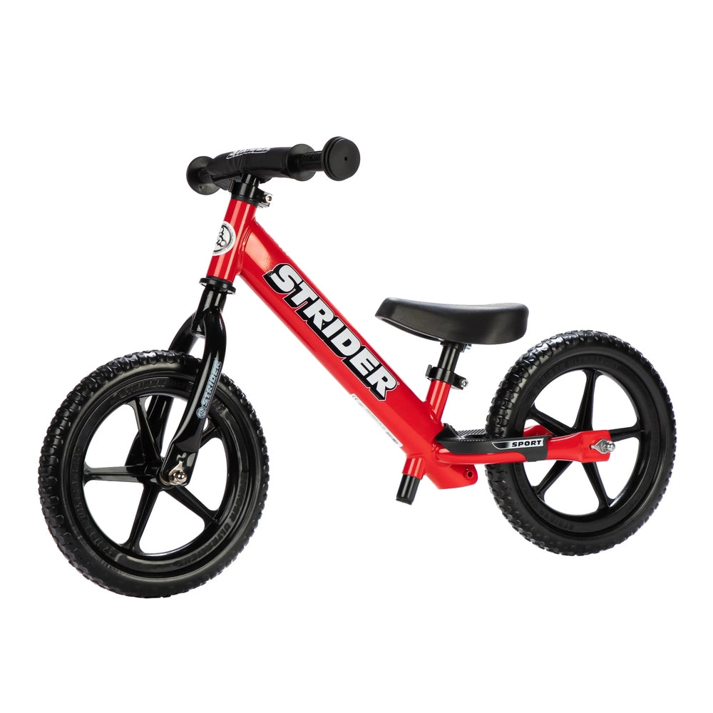 Strider 12 Sport balance bike, red frame with black wheels and seat, ready for a child to ride.