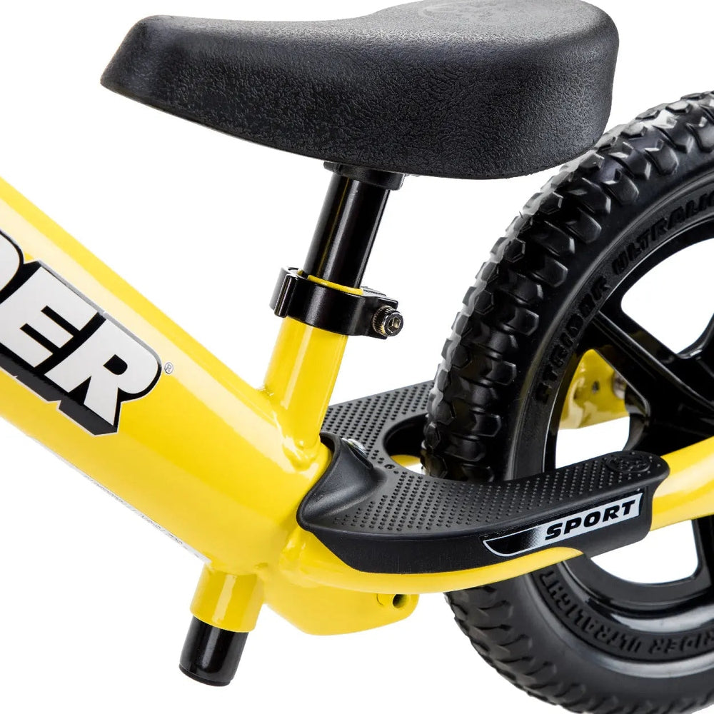 STRIDER 12 Sport balance bike, yellow frame with black saddle, adjustable seat post, and textured footboard.