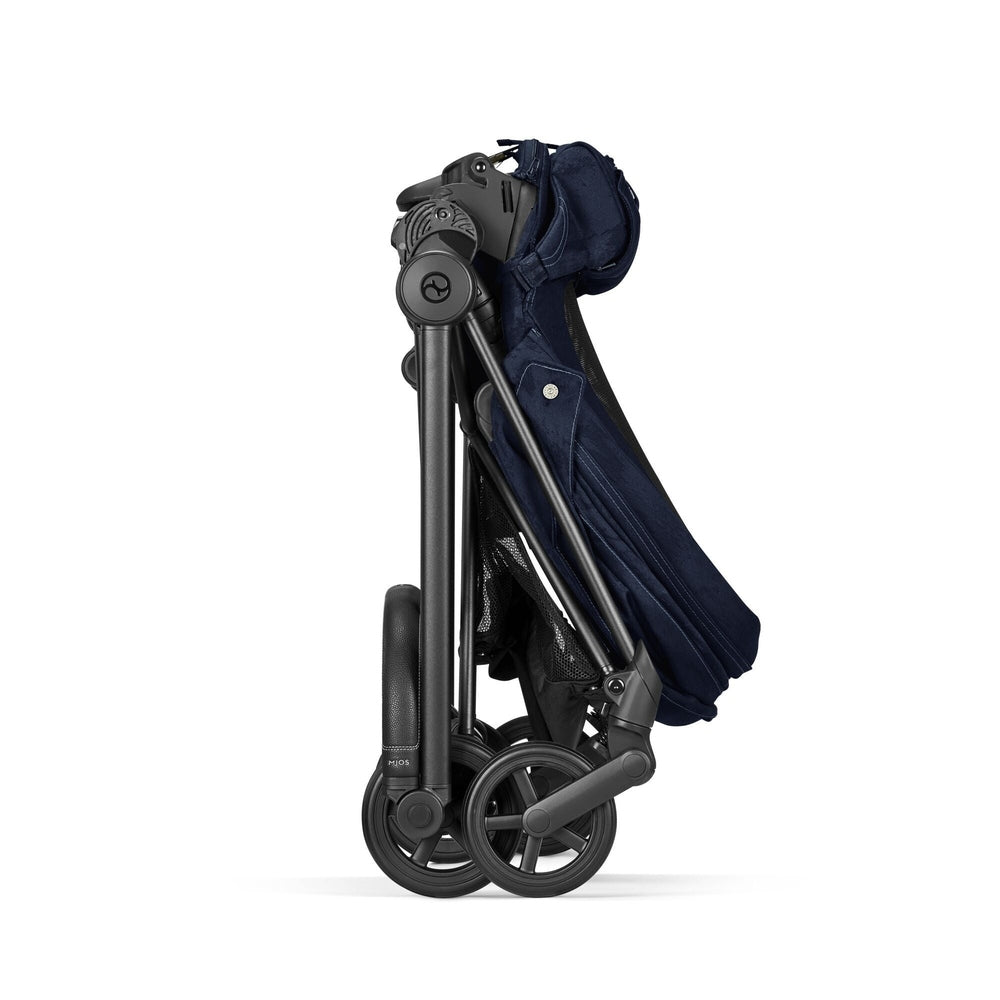 Studio product image of the Cybex Platinum Mios 3 Stroller Rebellious Luxury Denim Blue denim blue fabric, folded compact with dark frame and small black wheels on white background.