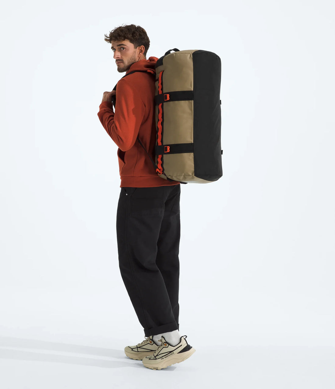 The North Face Base Camp Duffel - M - Cedar/TNF Black/Lava Red - carried by a model