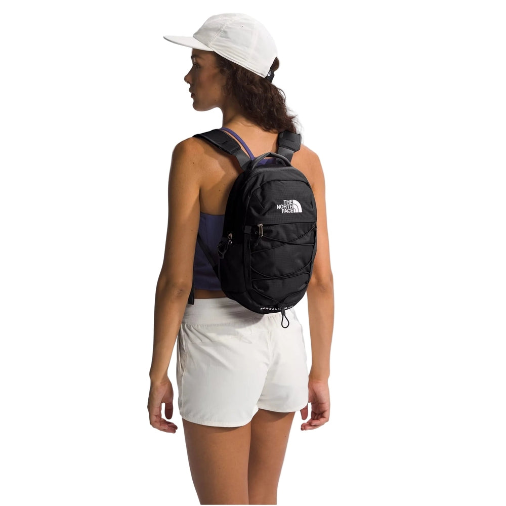 The North Face Borealis Mini Backpack in Black with white logo worn by a person in a white cap back view