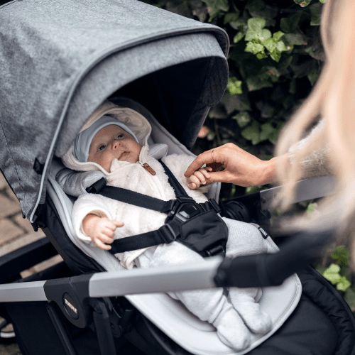 Thule Shine stroller in gray fabric with infant secured in harness