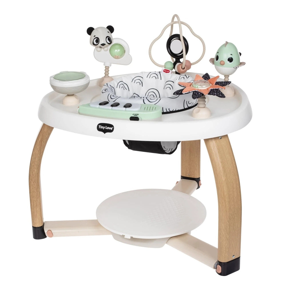 Tiny Love 5-in-1 Here Grow stationary activity center with white tray, wooden legs, and hanging toys as baby plays.