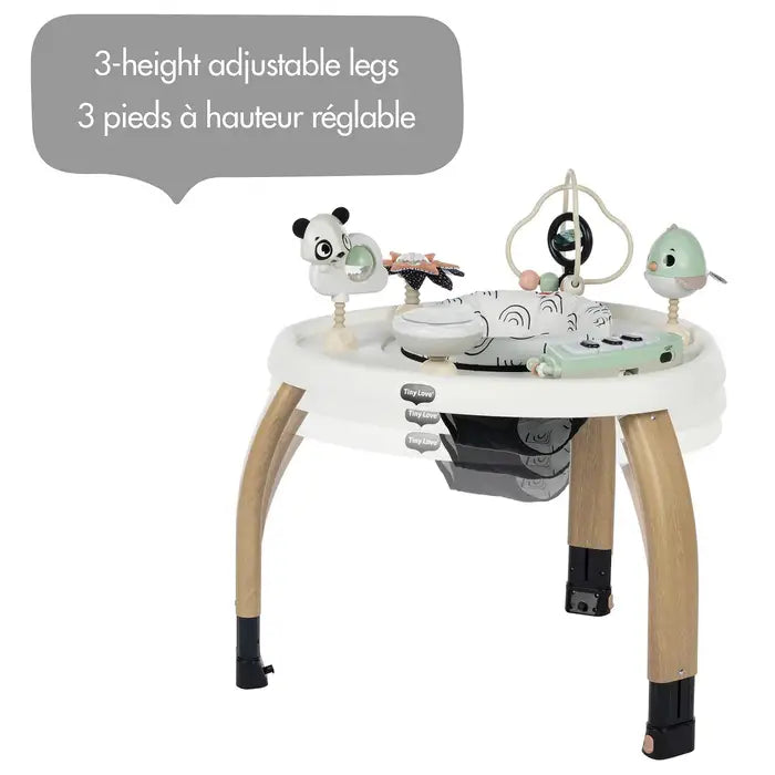 Tiny Love 5-In-1 Here I Grow Stationary Activity Center in white with natural wood legs, showing 3-height adjustable legs and hanging toys.