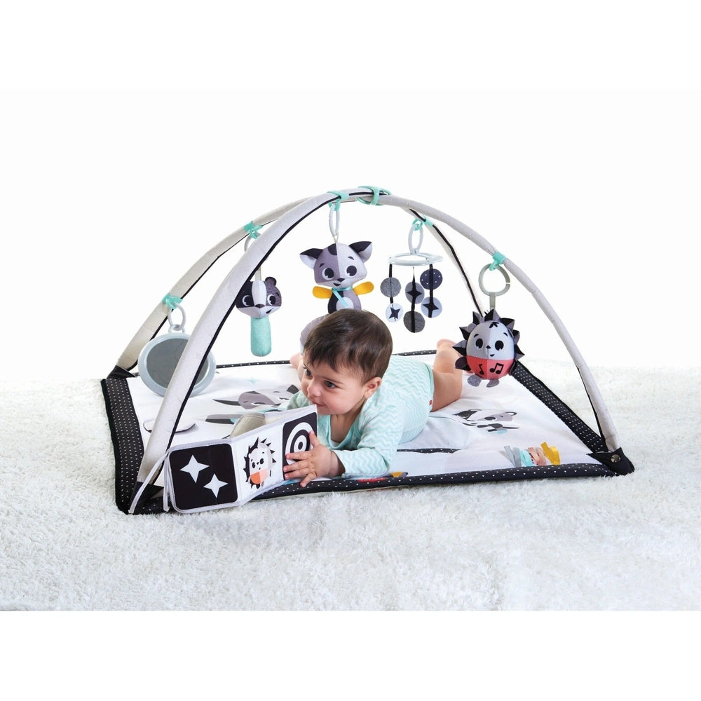 Tiny Love Magical Tales Black & White Gymini play mat with hanging plush toys, baby reaching inside the arched setup.