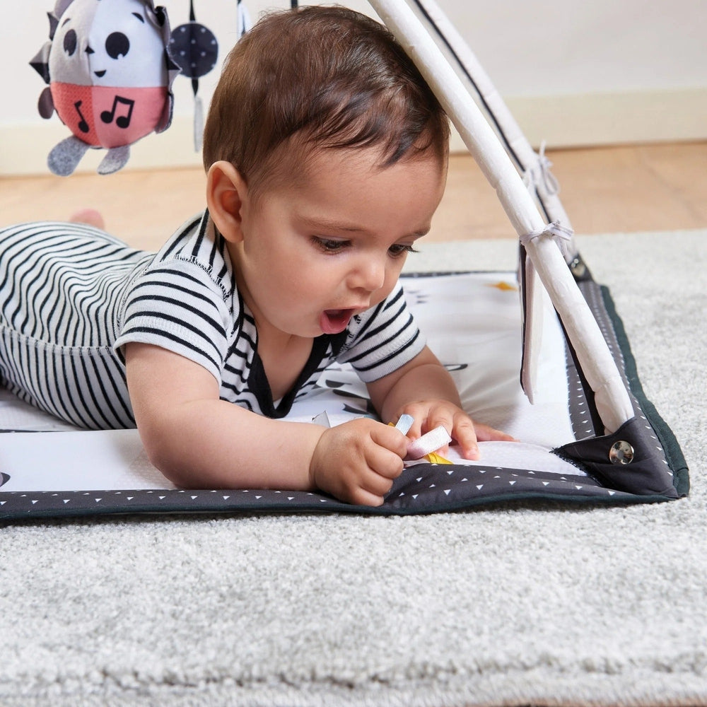 Tiny Love Magical Tales Black & White Gymini; baby on striped play mat reaching for a dangling toy.