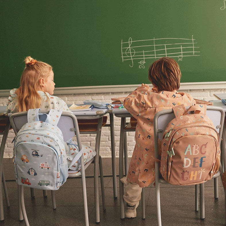 Tutete Kids Medium Backpack set: light blue vehicle-print backpack and peach ABC-letter backpack on two children.