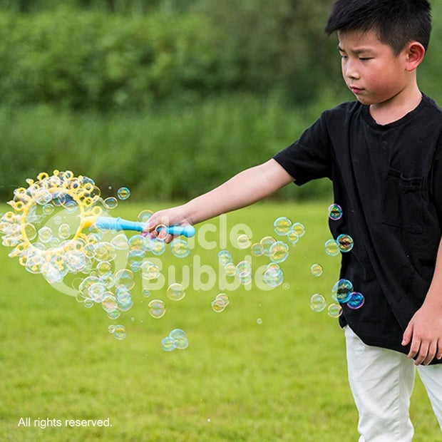 Uncle Bubble Fun Fantasy Wand 4 oz bubble blower toy, blue wand outdoors with bubbles