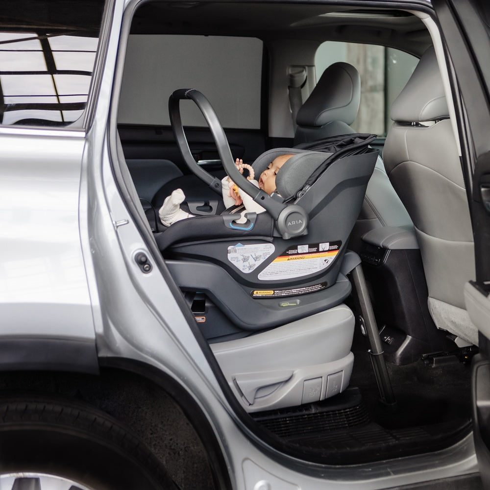 Child in a car seat inside a vehicle with an open door.