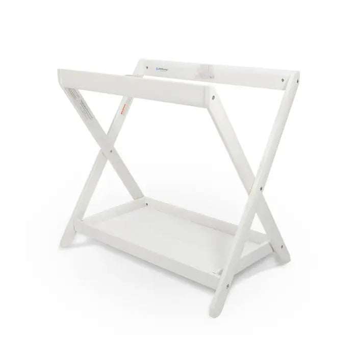 Uppababy Bassinet Stand, white wood X-frame with lower shelf, shown ready to cradle a bassinet.