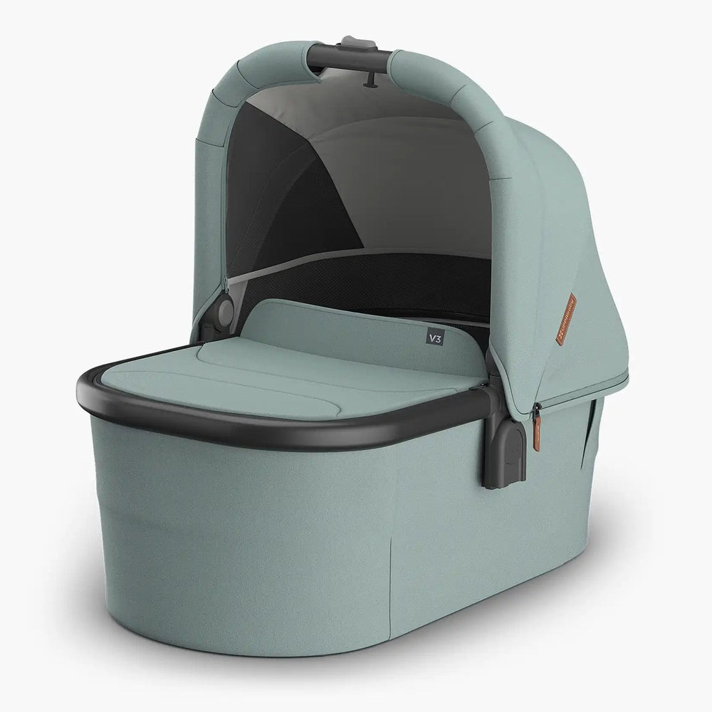 Uppababy Bassinet V3 in teal with canopy over a cushioned bassinet and built-in carry handle.