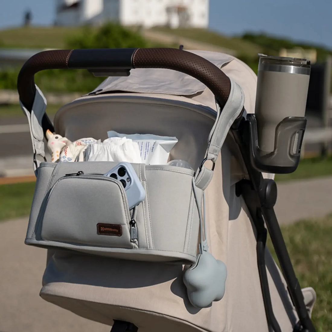 UPPAbaby Carry-All Parent Organizer in Light Grey on a stroller during an outdoor walk; other accessories sold separately