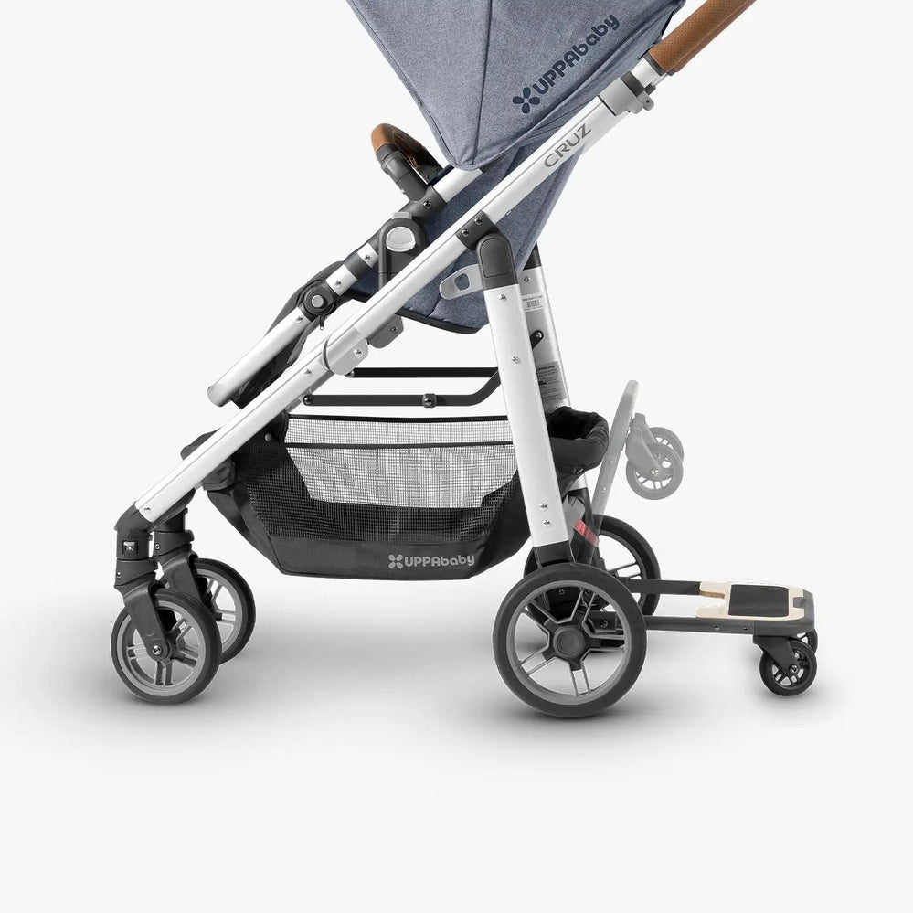 Side view of an UPPAbaby Cruz stroller with PiggyBack ride-along board attached at the rear, showing full stroller profile and board placement.