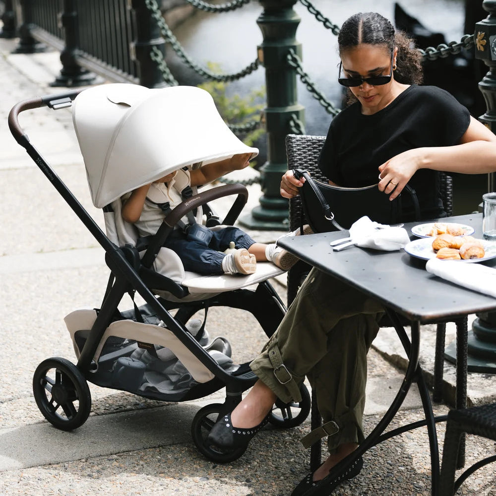 UPPAbaby Kona in Ada beside a cafe table