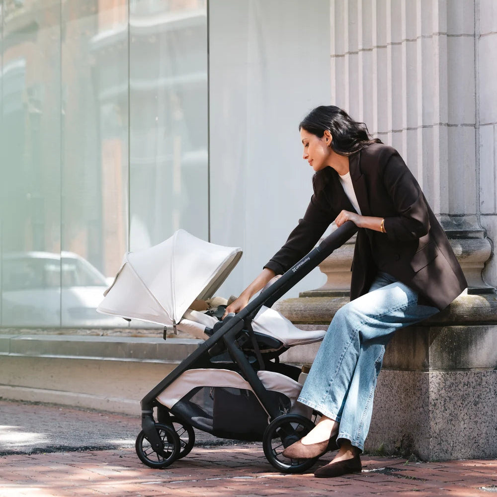 UPPAbaby Kona in Ada with the seat reclined beside a seated parent