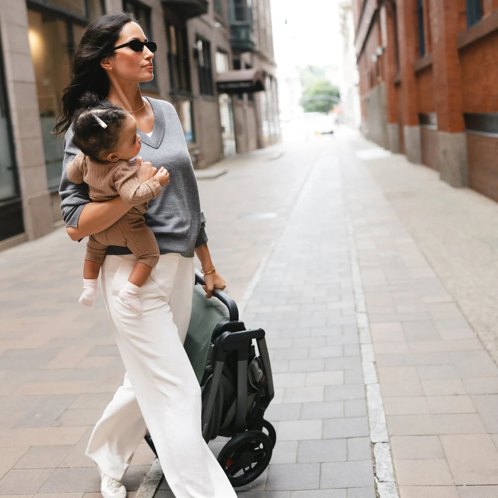 UPPAbaby Kona in Evelyn folded beside a parent and child