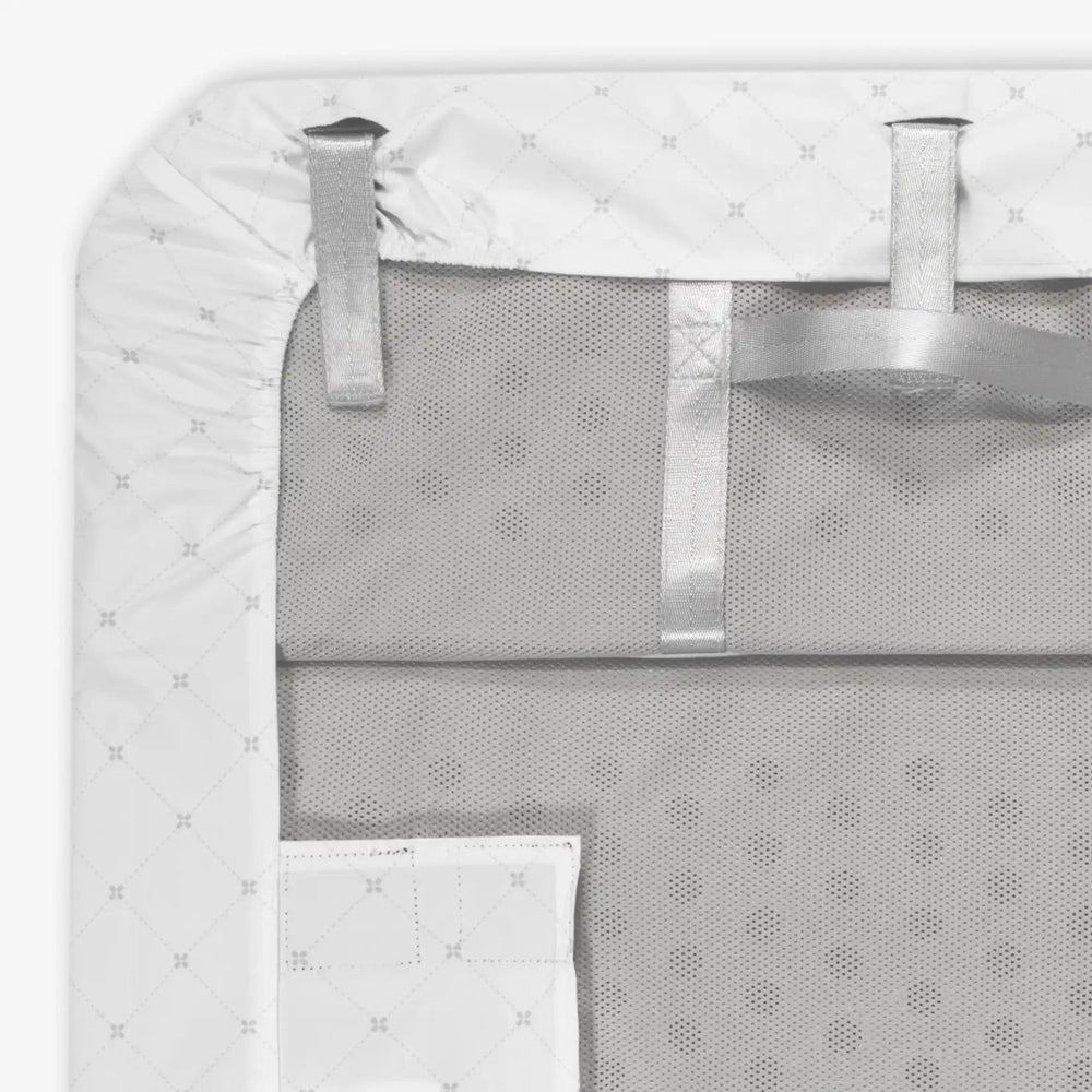 Uppababy Remi V1 waterproof bassinet mattress cover with white quilted top, securing straps, and breathable mesh backing