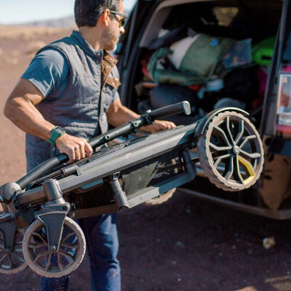 Veer All-Terrain Cruiser XL Wagon being loaded into a vehicle with large rugged wheels