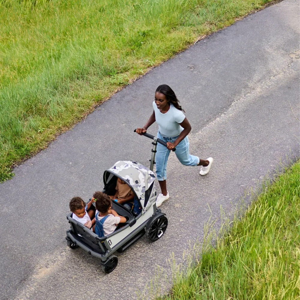 Woman pushing a stroller with children on a paved path