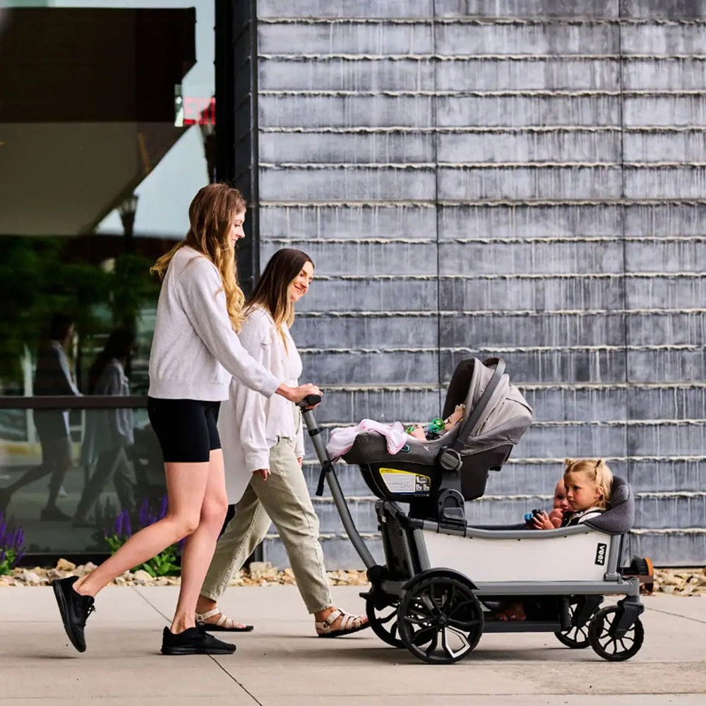 Two women pushing a stroller with a child on a sidewalk.