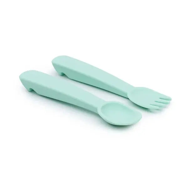 We Might Be Tiny Feedie fork and spoon set in mint green silicone, resting side by side on white background.