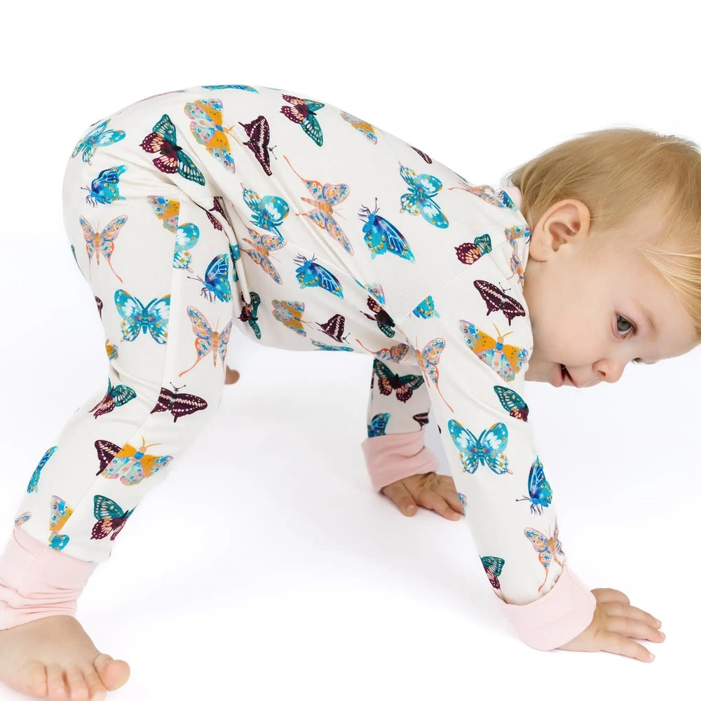 Baby wearing a butterfly-patterned onesie on a white background