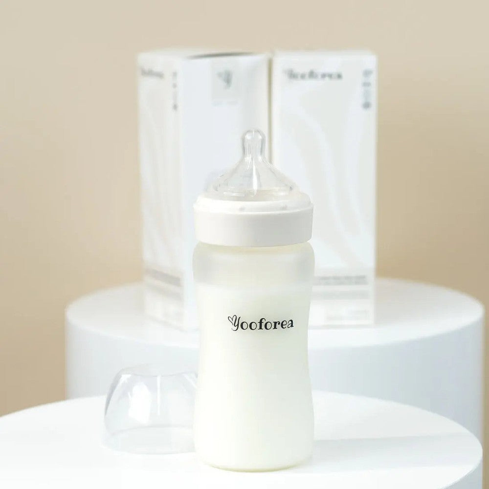 Yooforea Silicone Coated Glass Baby Bottle 9oz/270ml, clear nipple attached, stands on table.